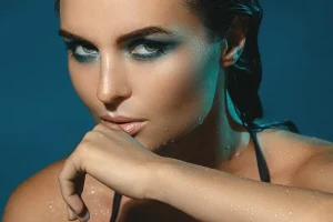 Close-up of woman with wet skin and intense makeup posing