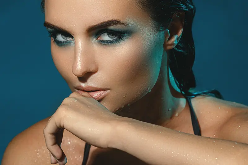 Close-up of woman with wet skin and intense makeup posing
